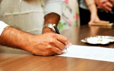 Close-up view of a person signing an important document with a pen on a wooden table.