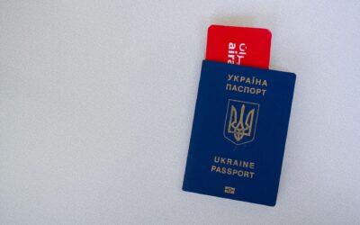 Close-up of a Ukrainian passport with an airline boarding pass on a white surface.