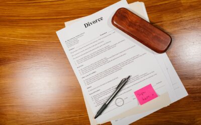 Flat lay of divorce papers with a pen and ring on a wooden table for legal themes.
