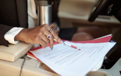 A professional reviewing documents in a car interior, focusing on hand and paperwork.